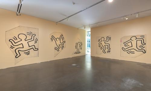 Image of a Keith Haring mural of man figures drawn with a black outline. 