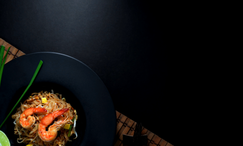 Shrimp and noodles in a bowl set on a black background