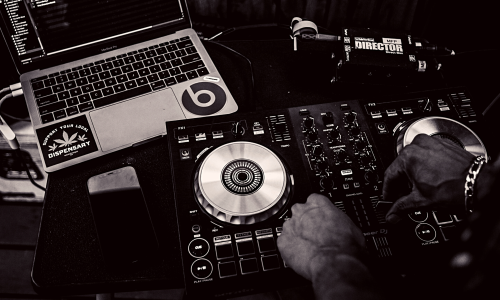 Photo of a DJ setup with a laptop in the left corner and turntables in the right