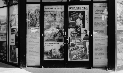 black and white photo of a vacant storefront with images and posters from Chicano creators of Denver's Northside neighborhood
