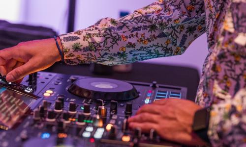 Close up of a DJ on a mixing board.