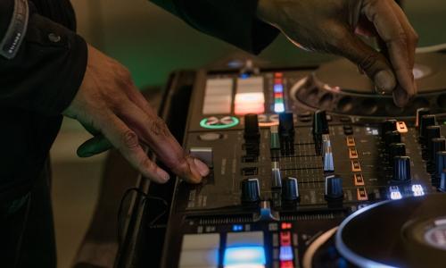 Close up of a DJ on a mixing board.