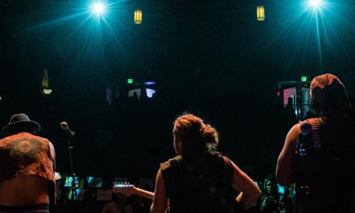 Band on a stage with their backs facing the camera.