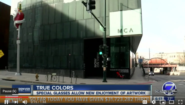 A screen capture of a news segment depicting the exterior of the MCA Denver. The news ticker reads: True Colors. Special glasses allow new enjoyment of artwork. 